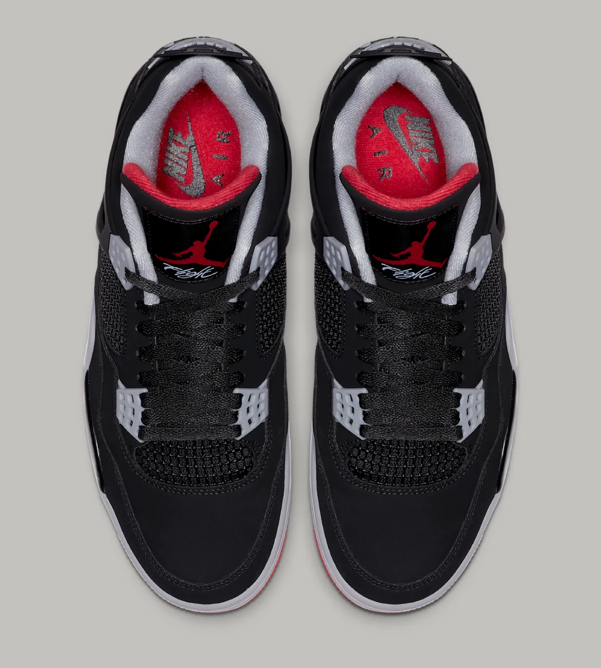 Air Jordan 4 Bred top-down pair view — black upper, cement grey wings, red Nike Air branding on the insole