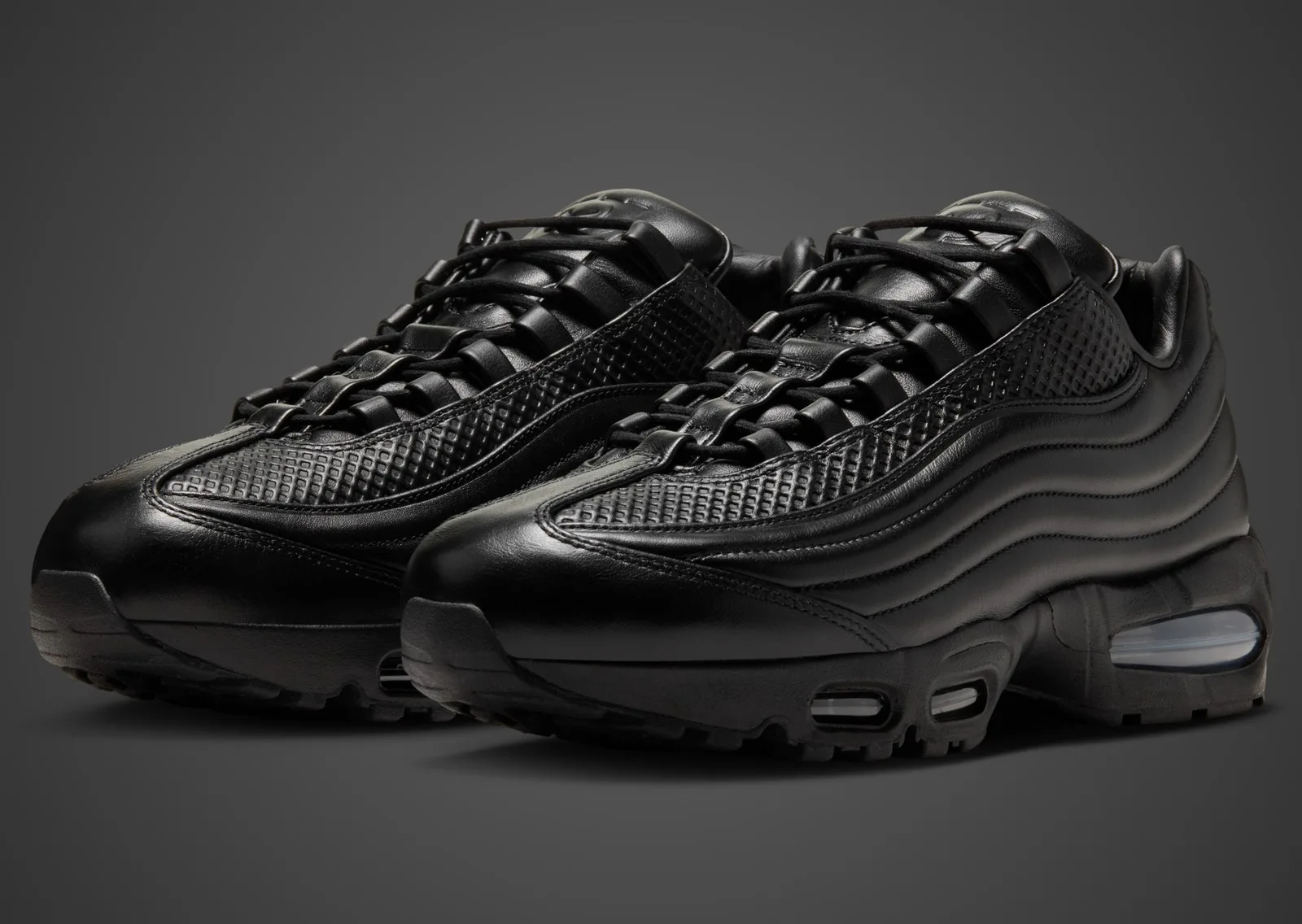 One Block Down x Nike Air Max 95 Lux Black — pair in all-black layered leather with clear Air units on a dark studio background